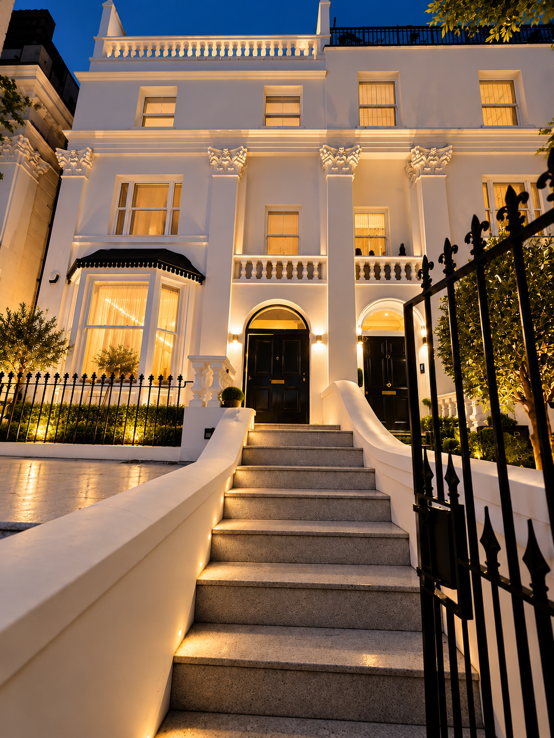 Floodlit white stucco townhouse entrance at night, renovated by I & S
