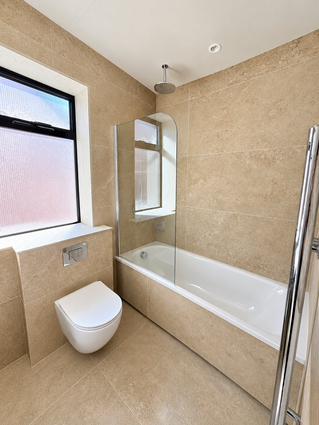 Bathroom with stone tiles, bath with glass screen and rainfall shower