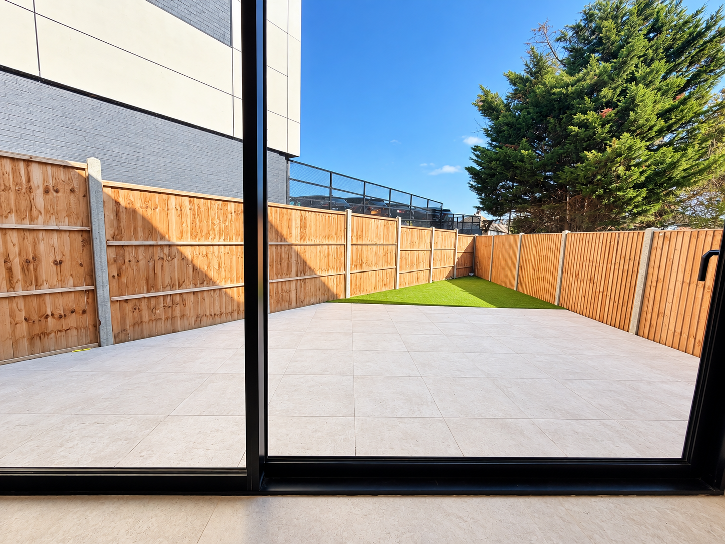Rear garden with stone patio, lawn and timber fencing