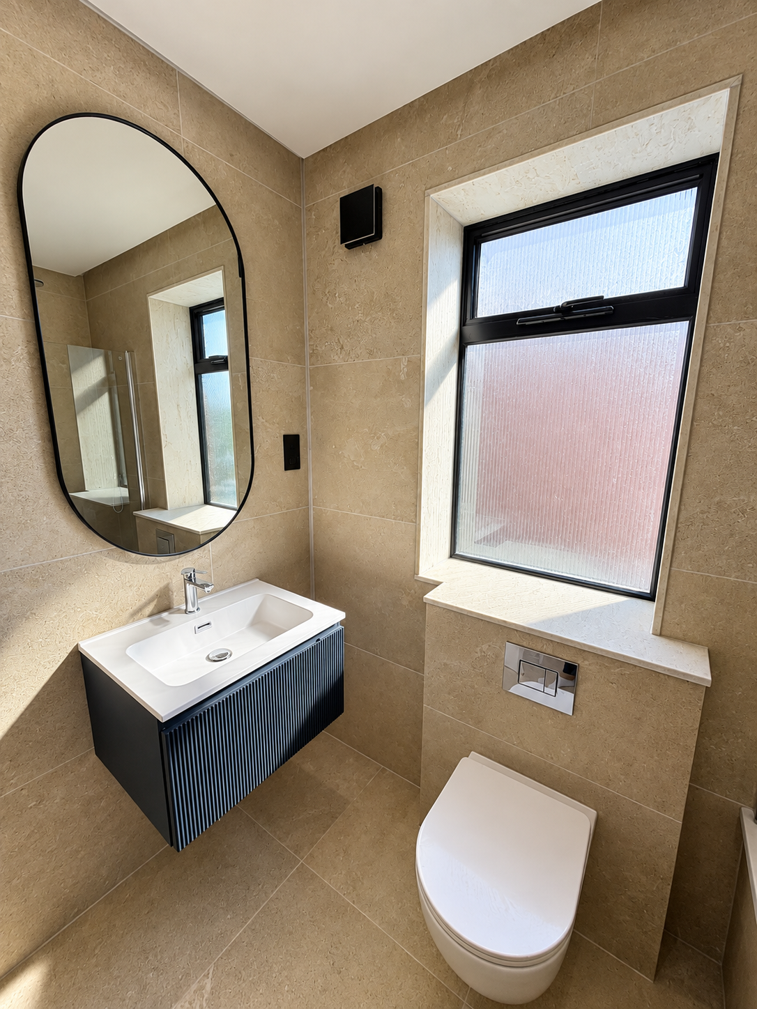 Family bathroom with beige stone tiles and black framed window