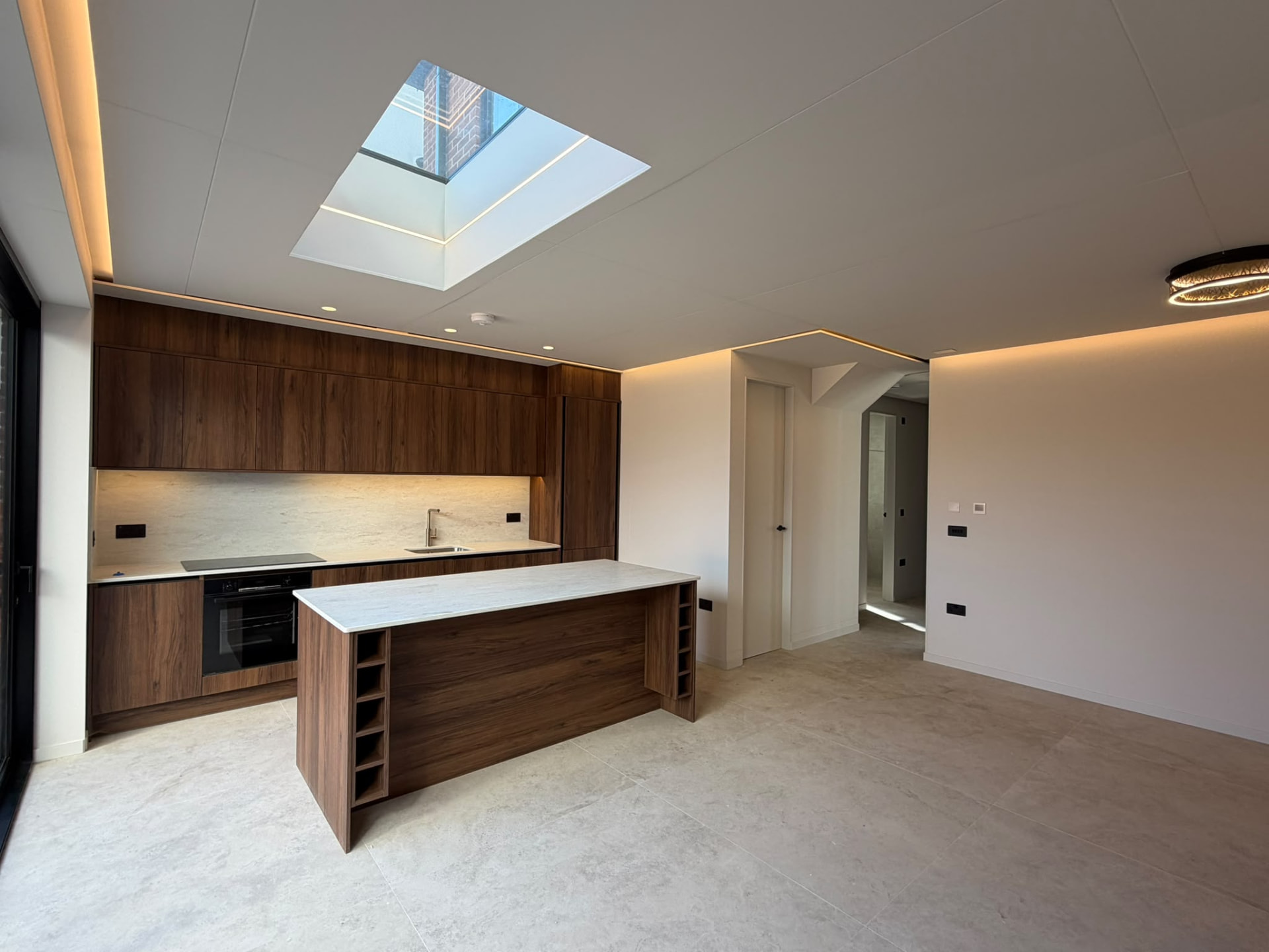 Walnut kitchen and island beneath a large rooflight
